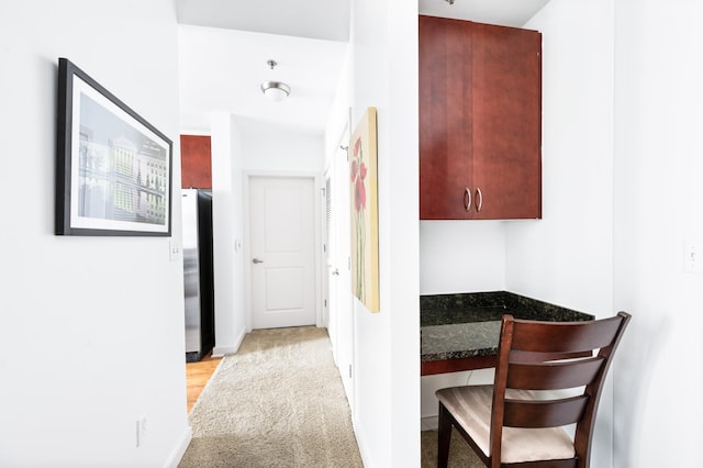 hallway featuring light carpet and baseboards