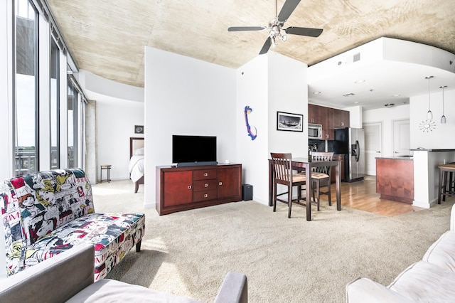 living room featuring light carpet, a ceiling fan, and baseboards
