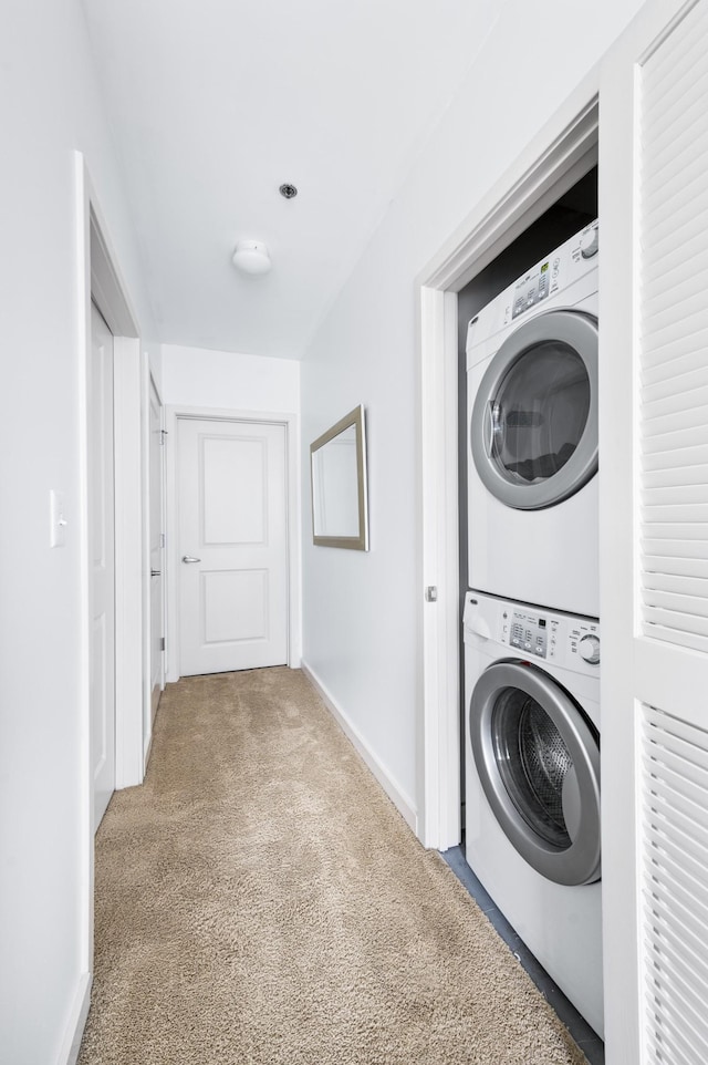 laundry area with estacked washer and dryer, carpet, and baseboards