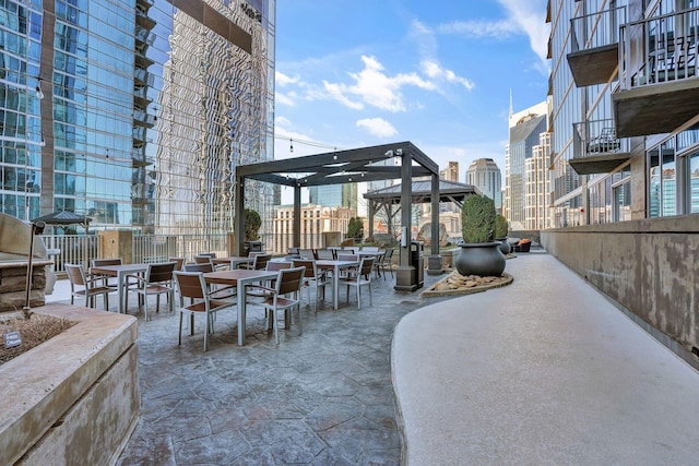 view of patio featuring outdoor dining space, a gazebo, a view of city, and fence