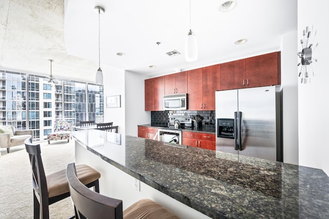 kitchen featuring stainless steel appliances, decorative backsplash, dark brown cabinets, decorative light fixtures, and a kitchen breakfast bar