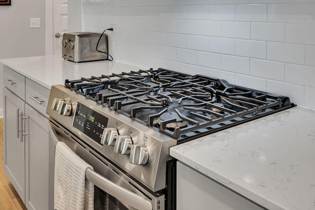 416 Golden Meadow Ln, Hendersonville, TN 37075 - kitchen view of stainless steel range with gas stovetop, tasteful backsplash, and light stone counters