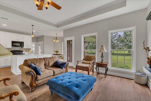 580 Laurel Ln, Murfreesboro, TN 37127 - living area featuring a tray ceiling, light wood-style flooring, ornamental molding, a ceiling fan, and a chandelier