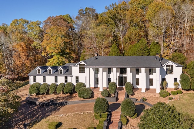 greek revival inspired property featuring solar panels and roof with shingles