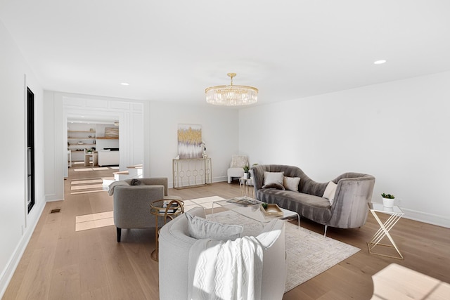 living area with a chandelier, light wood-type flooring, recessed lighting, and baseboards