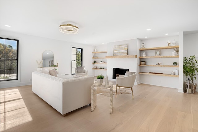 living room featuring light wood finished floors, a fireplace, recessed lighting, and baseboards