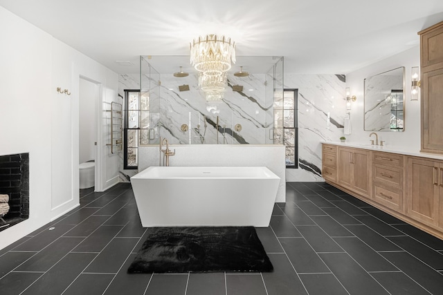 full bath featuring a marble finish shower, a chandelier, vanity, a freestanding bath, and toilet