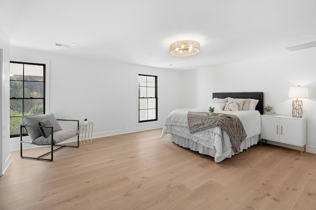bedroom featuring multiple windows, light wood-style flooring, and baseboards