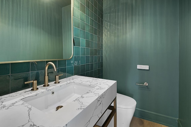 bathroom with vanity, toilet, decorative backsplash, and baseboards