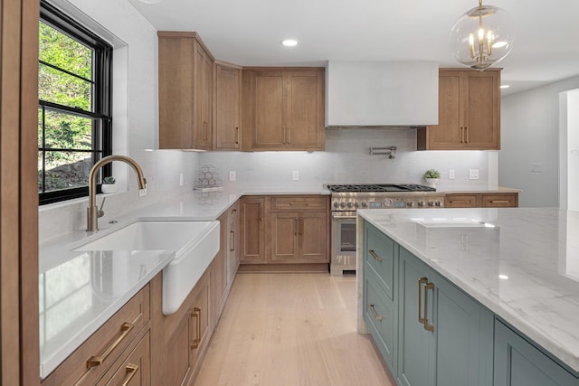 kitchen featuring a sink, light stone counters, light wood finished floors, backsplash, and recessed lighting