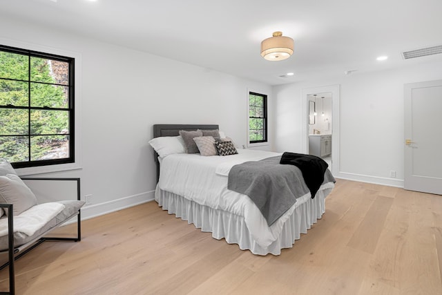 bedroom with light wood-type flooring, baseboards, recessed lighting, and ensuite bathroom