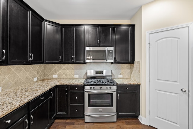 2044 Mainstream Dr, Franklin, TN 37064 - kitchen with stainless steel appliances, dark cabinetry, dark wood-type flooring, light stone counters, and decorative backsplash