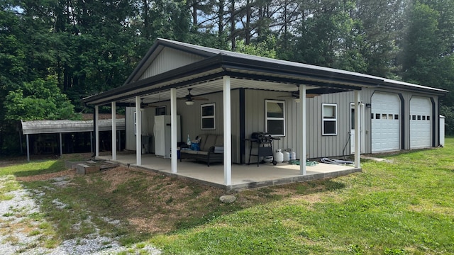 view of side of property featuring a ceiling fan, a garage, a lawn, and a patio area