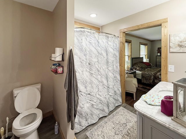 ensuite bathroom with wood finished floors, toilet, curtained shower, and vanity