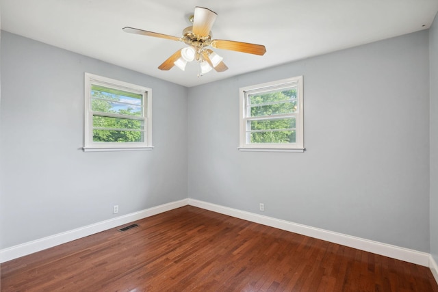 empty room with plenty of natural light, baseboards, dark wood-type flooring, and ceiling fan