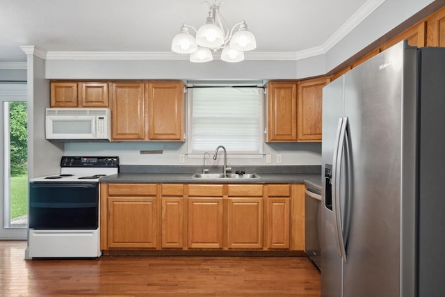 kitchen featuring appliances with stainless steel finishes, a sink, dark countertops, crown molding, and wood finished floors
