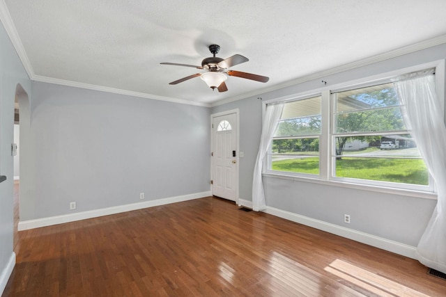 foyer with arched walkways, ceiling fan, wood finished floors, baseboards, and ornamental molding