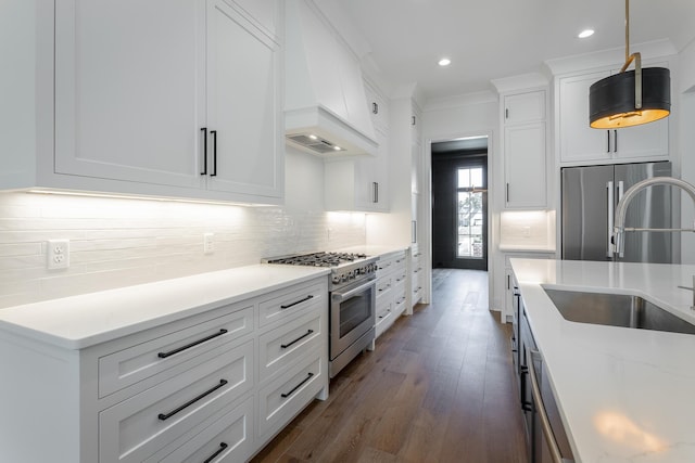kitchen with stainless steel appliances, a sink, dark wood-style flooring, decorative backsplash, and white cabinetry