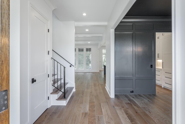 foyer with stairs, wood finished floors, recessed lighting, and a decorative wall