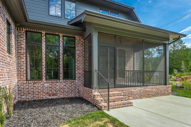 view of exterior entry with brick siding and a patio area