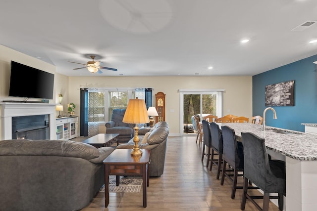 7587 Highborne Ln, Ooltewah, TN 37363 - living area featuring wood finished floors, a ceiling fan, a lit fireplace, and recessed lighting