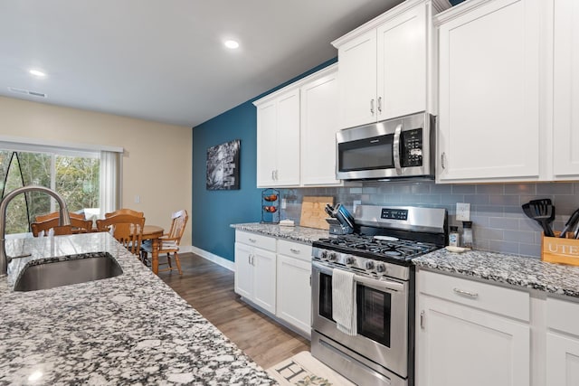7587 Highborne Ln, Ooltewah, TN 37363 - kitchen with appliances with stainless steel finishes, a sink, decorative backsplash, light wood-type flooring, and white cabinetry