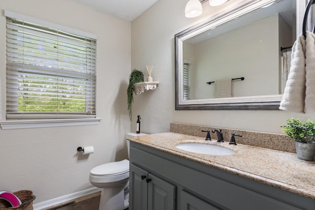 bathroom with vanity, baseboards, and toilet