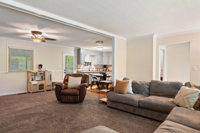 living room with crown molding, a textured ceiling, a ceiling fan, and baseboards