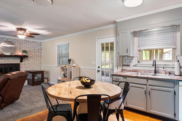 dining space with a textured ceiling, ornamental molding, ceiling fan, light wood-type flooring, and healthy amount of natural light