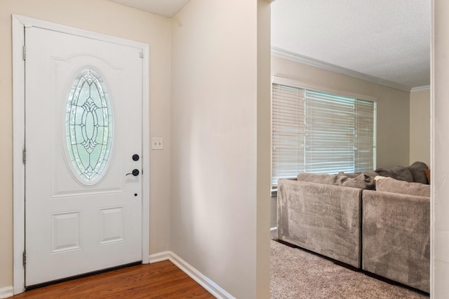 foyer entrance with ornamental molding, baseboards, wood finished floors, and a textured ceiling