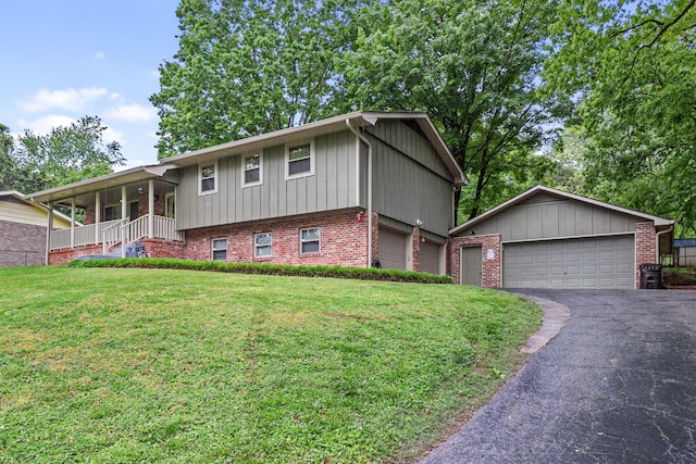 split level home with a front yard, brick siding, driveway, covered porch, and board and batten siding