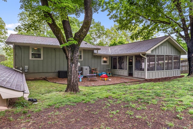rear view of property featuring board and batten siding, a sunroom, central air condition unit, and a yard