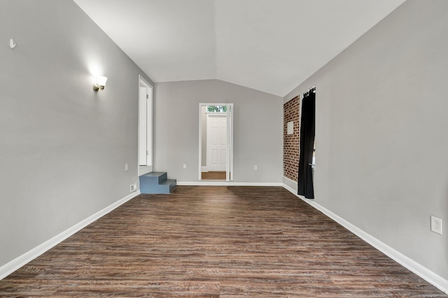 unfurnished living room featuring vaulted ceiling, dark wood finished floors, and baseboards