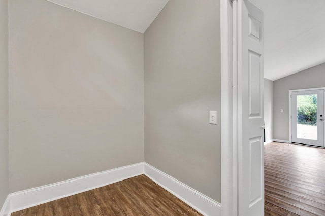 unfurnished room featuring vaulted ceiling, dark wood-style flooring, and baseboards