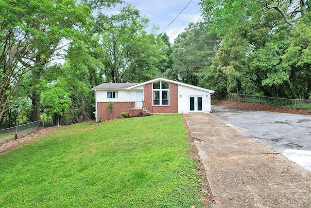 mid-century inspired home featuring french doors, brick siding, and driveway