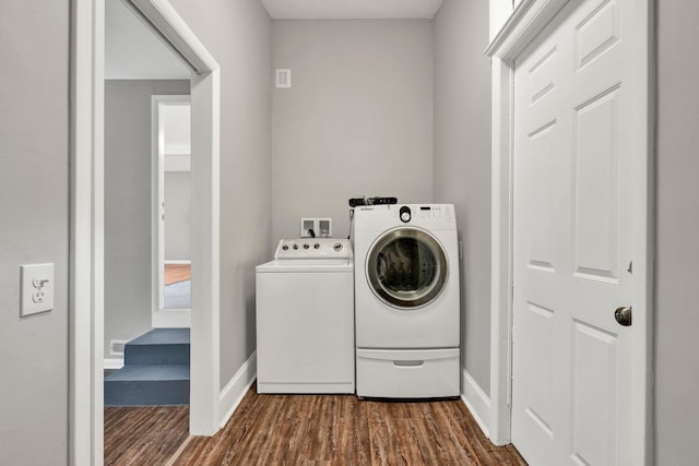 clothes washing area featuring washer and dryer, dark wood finished floors, and baseboards