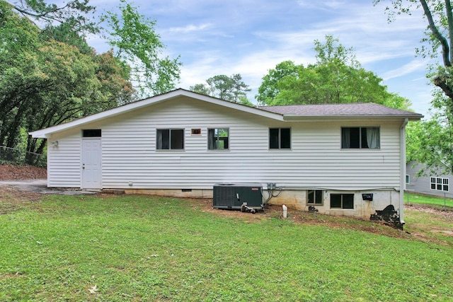 back of house with central AC unit and a lawn