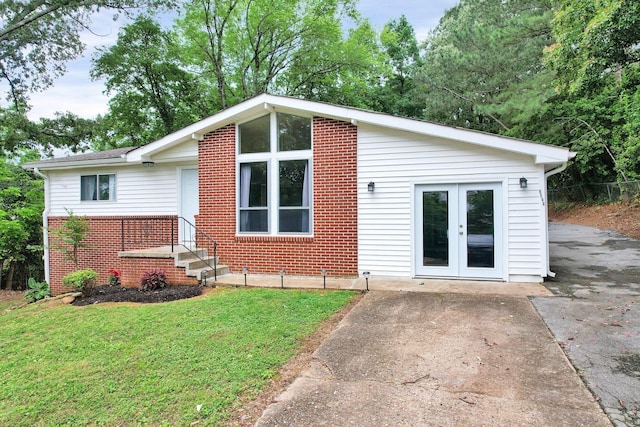 view of front of home featuring french doors, brick siding, and a front yard