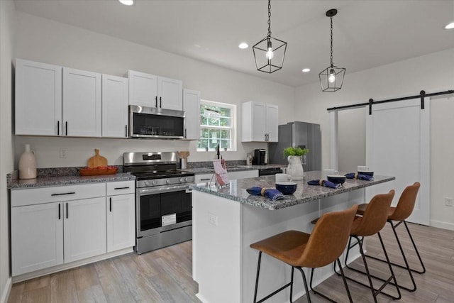 1014 Promise Land Rd, Charlotte, TN 37036 - kitchen with appliances with stainless steel finishes, a kitchen bar, recessed lighting, a barn door, and a center island