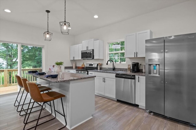 1014 Promise Land Rd, Charlotte, TN 37036 - kitchen with appliances with stainless steel finishes, a kitchen island, a breakfast bar area, light wood finished floors, and white cabinetry