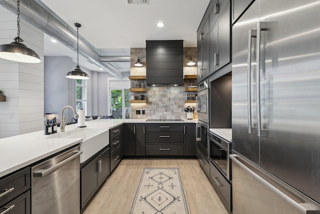 205 31st Ave N Unit 111, Nashville, TN 37203 - kitchen with appliances with stainless steel finishes, a sink, light wood-type flooring, wall chimney exhaust hood, and backsplash