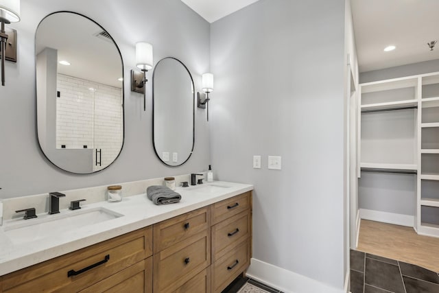 205 31st Ave N Unit 111, Nashville, TN 37203 - bathroom with baseboards, a shower stall, double vanity, a spacious closet, and recessed lighting
