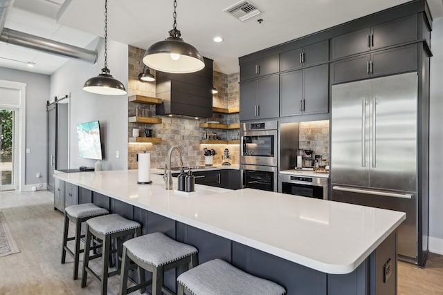 205 31st Ave N Unit 111, Nashville, TN 37203 - kitchen featuring stainless steel appliances, open shelves, light wood finished floors, baseboards, and backsplash