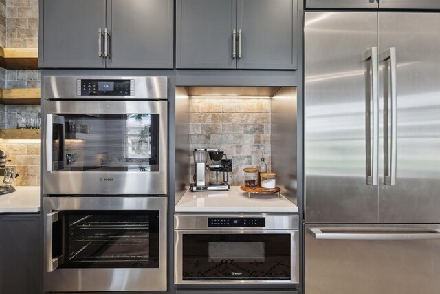 205 31st Ave N Unit 111, Nashville, TN 37203 - kitchen featuring appliances with stainless steel finishes, decorative backsplash, light countertops, and gray cabinets