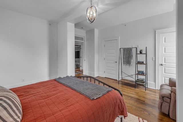 bedroom with wood finished floors, a chandelier, and baseboards