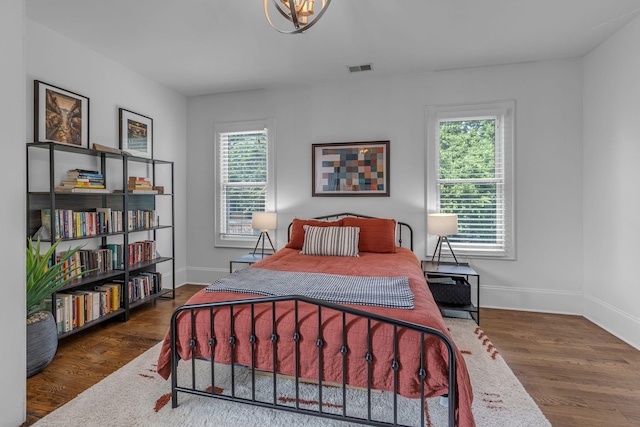 bedroom featuring multiple windows, baseboards, and wood finished floors