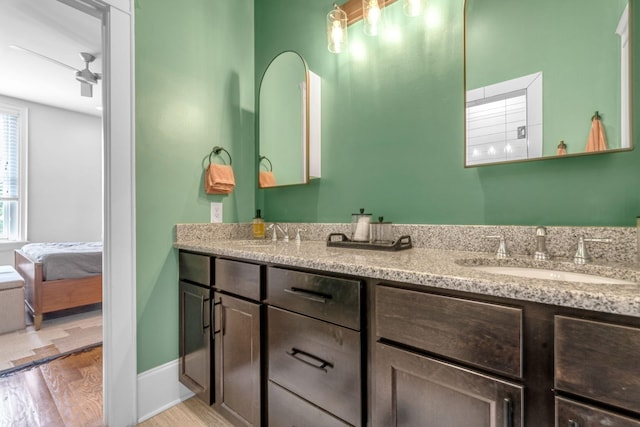bathroom featuring wood finished floors, double vanity, and baseboards