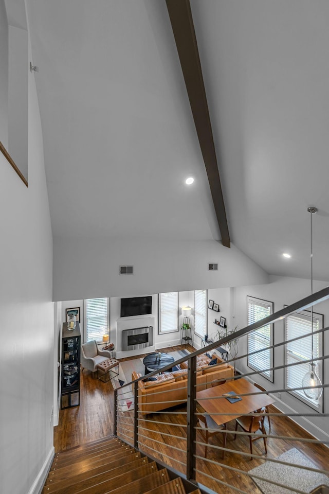 stairway with hardwood / wood-style floors, beam ceiling, recessed lighting, a fireplace, and high vaulted ceiling