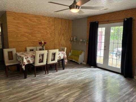 261 Oak Dr, Beechgrove, TN 37018 - dining space with a ceiling fan, wood finished floors, a textured ceiling, and wood walls