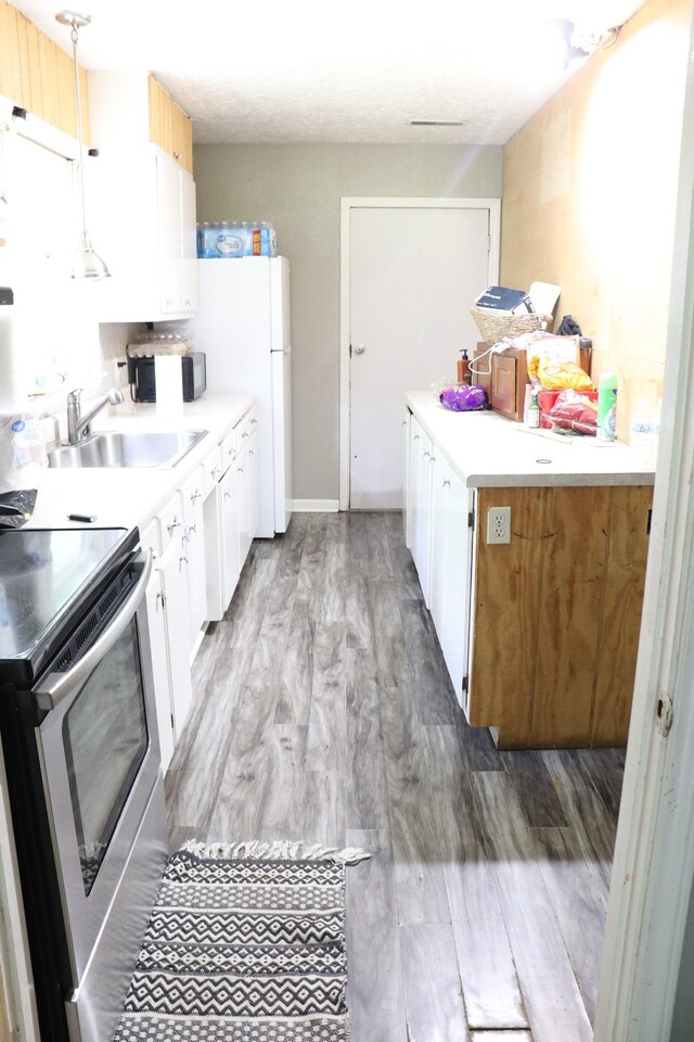 261 Oak Dr, Beechgrove, TN 37018 - kitchen with a sink, stainless steel range with electric cooktop, wood finished floors, and white cabinetry